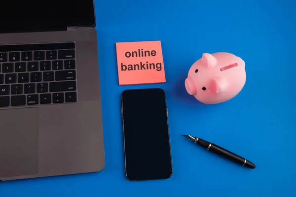 Piggy bank і гаджети з рожевою липкою нотою з повідомленням Online Banking, для концепцій онлайн або інтернет-банкінгу. — стокове фото