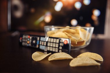 Ev konseptinde televizyon izlemek ve cam kaseden cips yemek.