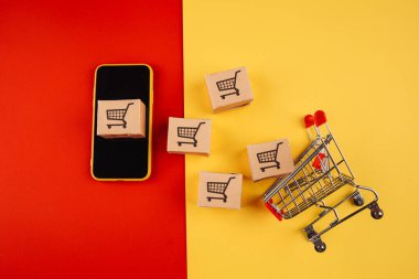 Akıllı telefondaki kağıt kahverengi kutular ve renkli arka plandaki tramvay izole edilmiş. Online mağazadan eve mal teslimatı konsepti