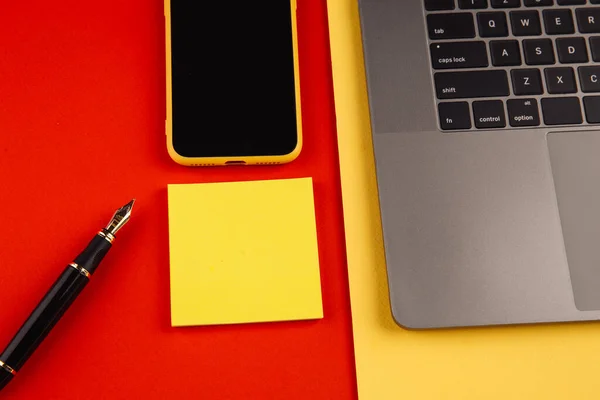 Concetto di scrivania per ufficio. Laptop, smartphone e penna con nota adesiva su sfondo rosso — Foto Stock