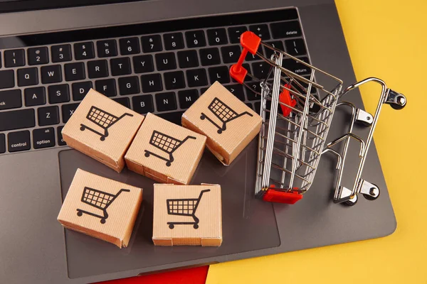 Concepto de compras online. Cinco cajas en el ordenador portátil y el carrito de compras aislados en fondo colorido — Foto de Stock