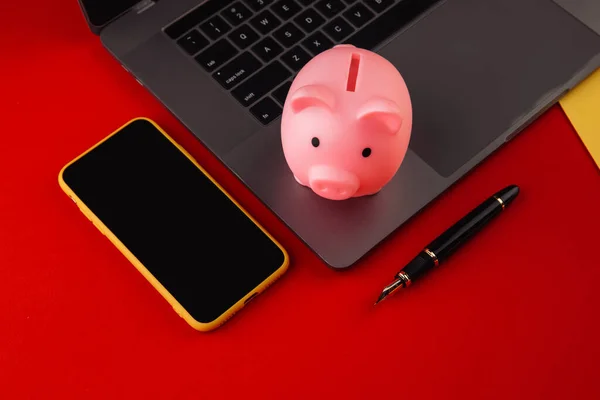 Moneybox w pobli? u laptopa i smartfona, miejsce na tekst. Koncepcja finansów i budżetu. Piggy bank w kolorze różowym z gadżetów i papeterii na kolorowym tle — Zdjęcie stockowe