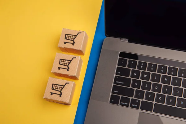 Concetto di shopping online. Laptop con mini scatole su sfondo blu giallo — Foto Stock