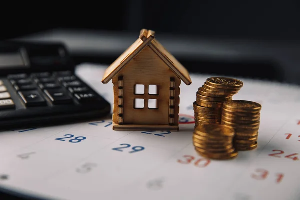 Giorno per pagare il mutuo, l'acquisto di nuova pianificazione della casa o immobiliare e concetto di promemoria immobiliare. Casa in legno su calendario bianco con calcolatrice e monete — Foto Stock