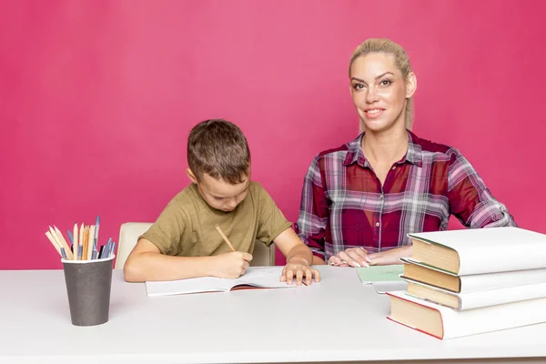 隔離時に自宅で母親との距離宿題。机に座って勉強してるママと男の子. — ストック写真