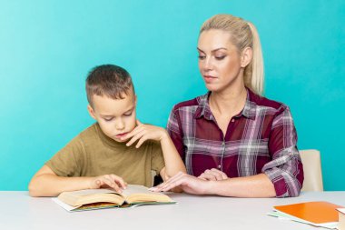 Annesiyle ödev yapan küçük bir okul çocuğu, aile içi işbirliği, ebeveynlik.