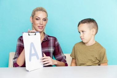 Annesiyle ödev yapan küçük bir okul çocuğu, aile içi işbirliği, ebeveynlik.