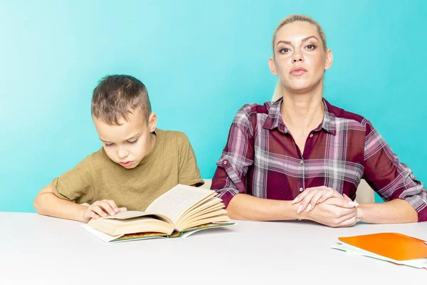 Mutter hilft ihrem Sohn bei den Hausaufgaben vor isoliertem rosa Hintergrund. Distanzierte Bildung — Stockfoto