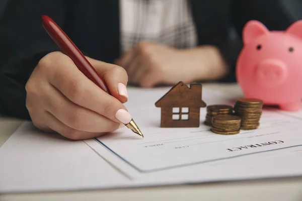 Fechar casa de brinquedo de madeira com mulher assina um contrato de compra ou hipoteca para uma casa, conceito imobiliário . — Fotografia de Stock