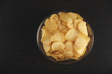 Siyah masada bir tabak patates cipsi..