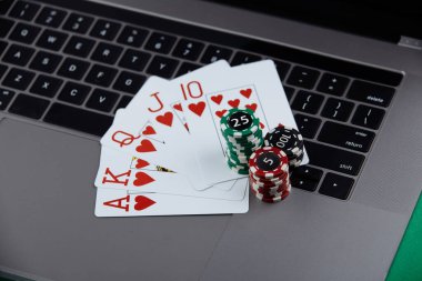 Bir yığın poker fişi ve dizüstü bilgisayarda iskambil kartları. Kumarhane ve poker online konsepti