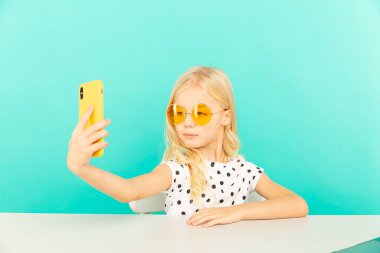 Evde kameranın önünde vlog için konuşan mutlu kız. çocuk kendi fotoğrafını ve videosunu çekiyor blog yazarı olarak çalışıyor, internet için video dersi kaydediyor.