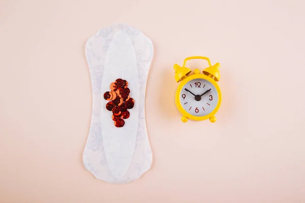 Menstruációs női higiénia koncepció. Minimális lapos feküdt menstruációs pad és sárga ébresztőóra rózsaszín alapon — Stock Fotó