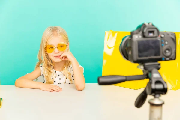 Gelukkig meisje in de blauwe studio spreekt voor de camera voor vlog. Werken als blogger, video-tutorial opnemen voor internet. — Stockfoto