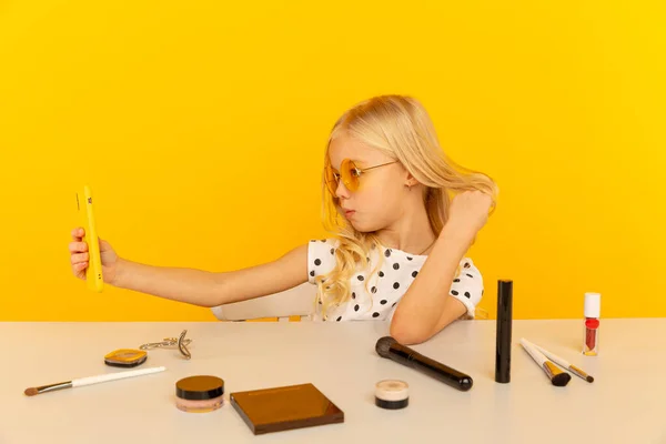 카메라 앞 노란색 스튜디오에 있는 어린 소녀 블로거가 비디오를 만들고 있습니다. 블로거로 일하면서 인터넷용 비디오 테 잎을 녹음하는 모습. — 스톡 사진