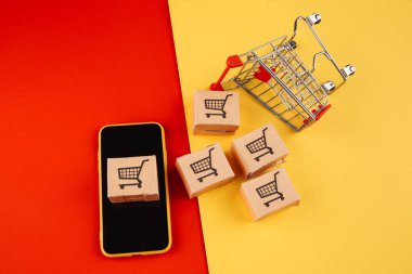 Akıllı telefondaki kağıt kahverengi kutular ve renkli arka plandaki tramvay izole edilmiş. Online mağazadan eve mal teslimatı konsepti