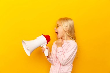 Çocuk megafonla bağırıyor. İletişim konsepti. Metnin için kopyalama alanı olarak sarı arkaplan