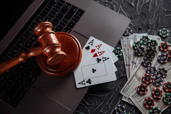 Online gambling and justice theme, cards, playing chips and judge wooden gavel on laptop keyboard