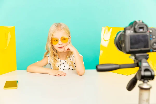 Gelukkig meisje in de blauwe studio spreekt voor de camera voor vlog. Werken als blogger, video-tutorial opnemen voor internet. — Stockfoto