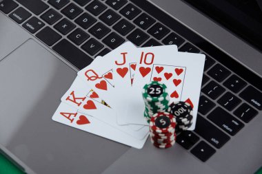 Bir yığın poker fişi ve dizüstü bilgisayarda iskambil kartları. Online kumarhane konsepti