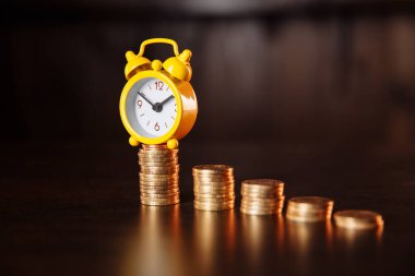 Zaman ve para arasındaki ilişki hakkında bir kavram. Bir çalar saat ve bozuk para yığını