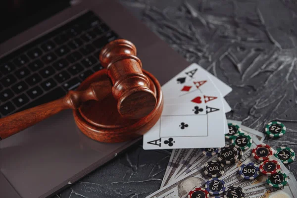 Law and rules for online gambling concept, judge gavel with playng cards and money banknotes on laptop computer keyboard