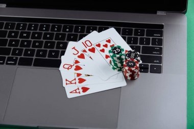 Bir yığın poker fişi ve dizüstü bilgisayarda iskambil kartları. Kumarhane ve poker online konsepti
