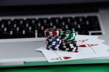 Bir yığın poker fişi ve dizüstü bilgisayarda iskambil kartları. Online kumarhane konsepti