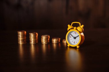 Para yığını ve ahşap arka planda alarmlı işletme finansal fikirleri kavramı