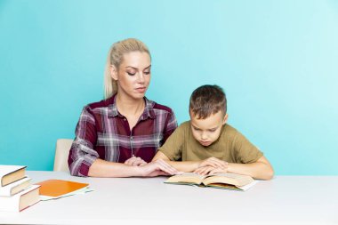Karantina zamanında annemle evden uzak ev ödevi. Çocuk ve anne masada oturuyor ve ders çalışıyorlar..