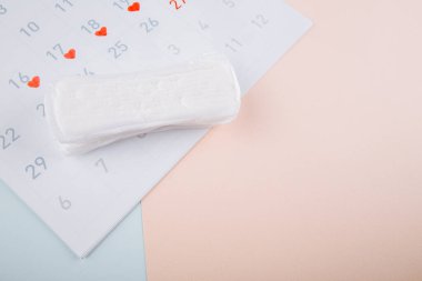 Adet gören kadın hijyen konsepti. Minimum düz yatay adet pedi ve mavi pembe arka plan takvimi