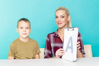 Anne, oğluna pembe arka planda ödevlerinde yardım ediyor. Uzak eğitim
