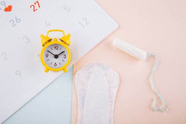 Regl takvimi, çalar saat ve pamuklu ped. Adet dönemi konsepti. Adet sancısı için ağrı kesici.