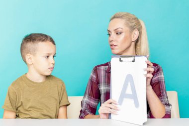 Anne, oğluna pembe arka planda ödevlerinde yardım ediyor. Uzak eğitim