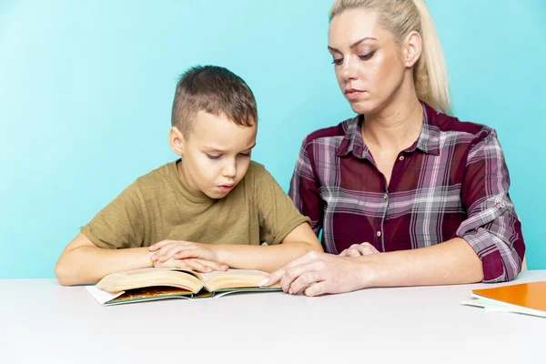 Mother helping her son with homework over isolated pink background. Distant education — Stock Photo, Image