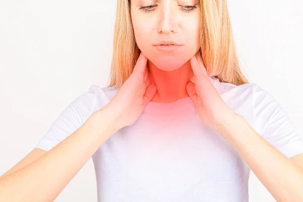 Femme vérifiant la glande thyroïde toute seule. Gros plan de la femme en t-shirt blanc touchant le cou avec une tache rouge. Le trouble thyroïdien comprend le goitre, l'hyperthyroïde, l'hypothyroïde, la tumeur ou le cancer. Soins de santé. — Photo