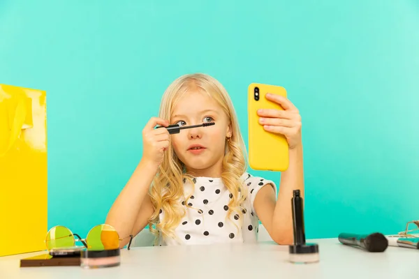 Een klein meisje dat make-up doet op camera voor vlog. Werken als blogger, video-tutorial opnemen voor internet. — Stockfoto