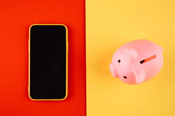 マネーボックスと携帯電話。財政と予算の概念。ピギーバンクでピンク色とともにガジェット上のカラフルな背景 — ストック写真