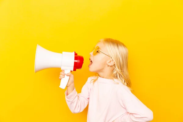 Kid shouting through megaphone. Communication concept. yellow background as copy space for your text — Stock Photo, Image