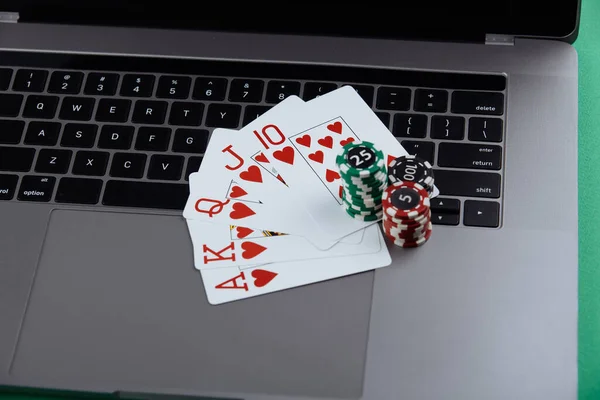 Tumpukan chip poker dan bermain kartu di komputer laptop. Casino dan konsep online poker Stok Foto