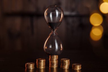 İçinde bir yığın bozuk para olan kum saati. Zaman paradır, yatırım konsepti