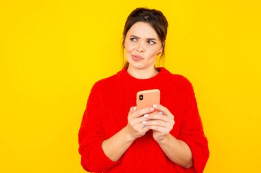 Telefonu olan genç bir kadının sarı arka planda izole edilmiş olduğunu düşünüyorum..