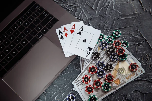 Stacks of poker chips, money banknotes and playing cards on a laptop computer. Online casino concept