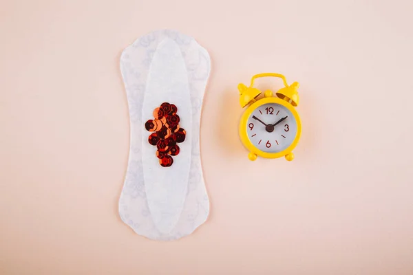 Hygienbegreppet menstruationskvinna. Minimal platt låg menstruation pad och gul väckarklocka på en rosa bakgrund — Stockfoto