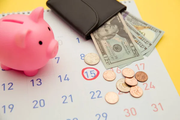 Time to invest,business concept. Pink piggy bank and wallet with money banknotes, calendar on yellow background — Stock Photo, Image