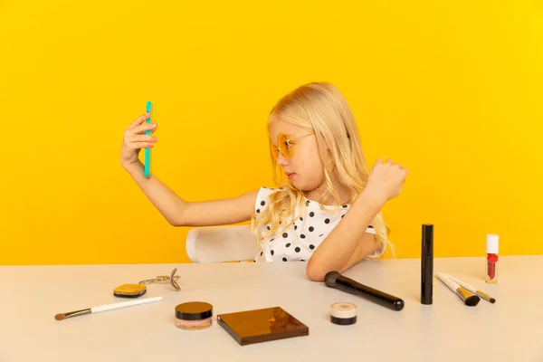 카메라 앞 노란색 스튜디오에 있는 어린 소녀 블로거가 비디오를 만들고 있습니다. 블로거로 일하면서 인터넷용 비디오 테 잎을 녹음하는 모습. — 스톡 사진