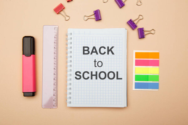 School office supplies on pink background and notebook with BACK TO SCHOOL