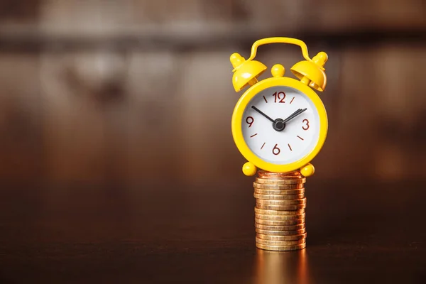 A concept about the relationship between time and money. An alarm clock and stack of coins — Stock Photo, Image