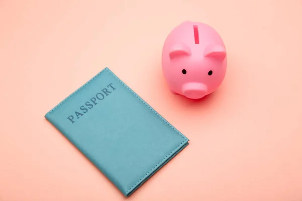 Save up for traveling. Piggy bank with passport on pink background. Top view. Flat lay
