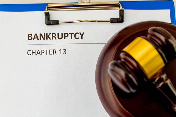 Петиция о банкротстве и деревянный молоток за столом.